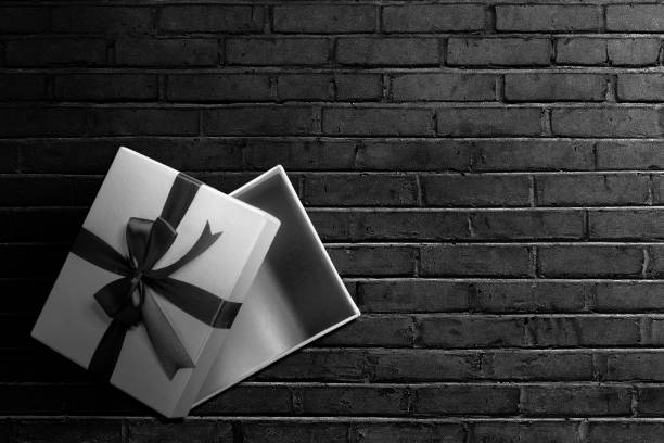 istock Opened a white gift box with a black ribbon with a black wall background 1359095102