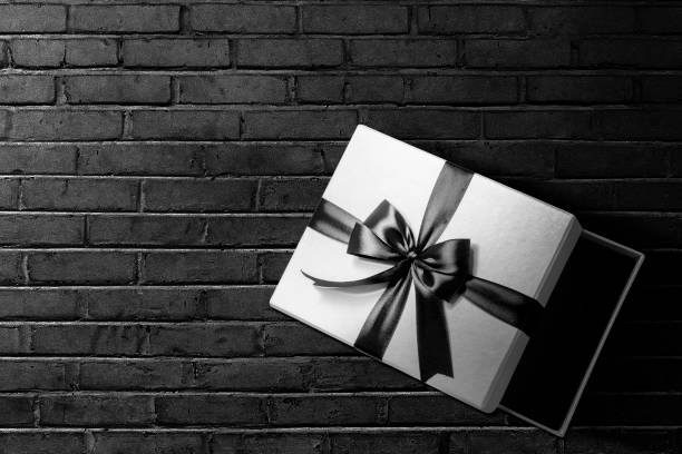 istock Opened a white gift box with a black ribbon with a black wall background 1359095111