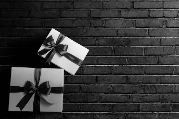 istock White gift box with a black ribbon with a black wall background 1359095493