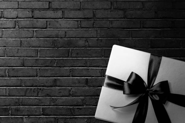 istock White gift box with a black ribbon with a black wall background 1359095503