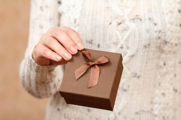 istock Woman holding a brown gift box in the hand. 1359096816