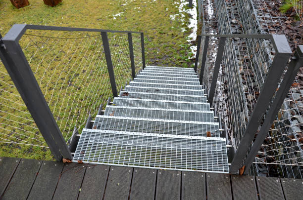 istock construction of a steep staircase by the stone wall car park with high durability even under heavy load galvanized steel floor grate and railings. gabion above him a wire fence. corridor, narrow 1359099432