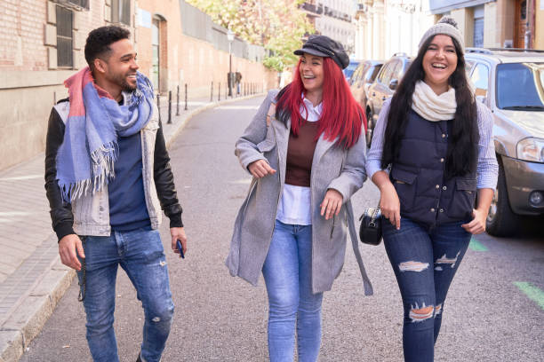 istock Stylish diverse friends walking on road and talking to each other 1359101892