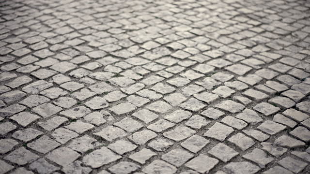 Ancient sett road of paving stones. Pedestrian sidewalk of cobblestone pavement.