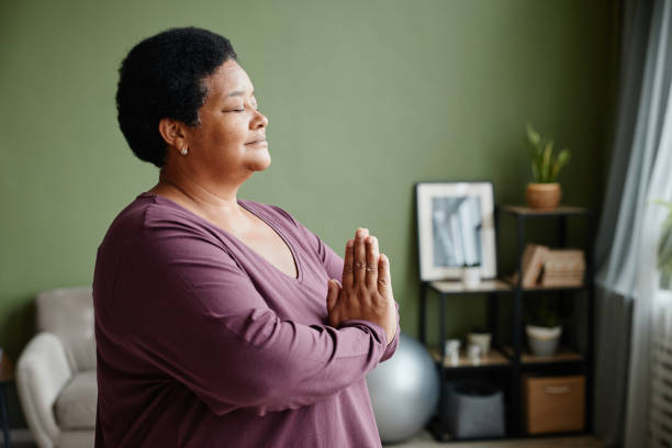 senior woman meditating at home side view - spiritual practices imagens e fotografias de stock