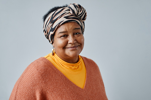 Portrait of black senior woman wearing ethnic prints and looking at camera smiling against white background, copy space