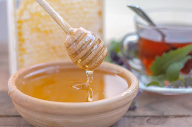 istock honey flows into a bowl with a honey wooden spoon 1359105571