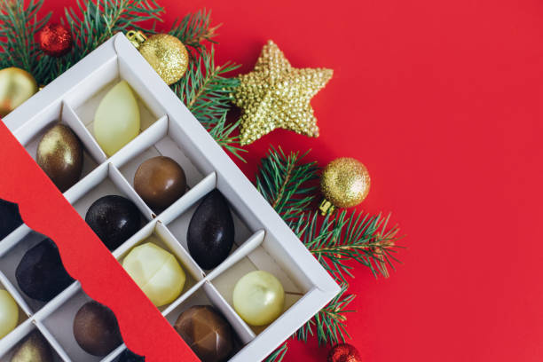 istock Gift box with  chocolate candies, spruce branches, red and golden balls on a red background. 1359108548