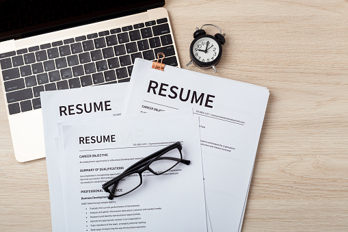 Resumes on laptop with glasses on wood desk, resume review, job interview, top view