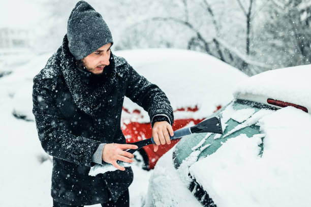 istock Young Man cleans car glass from ice 1359110201