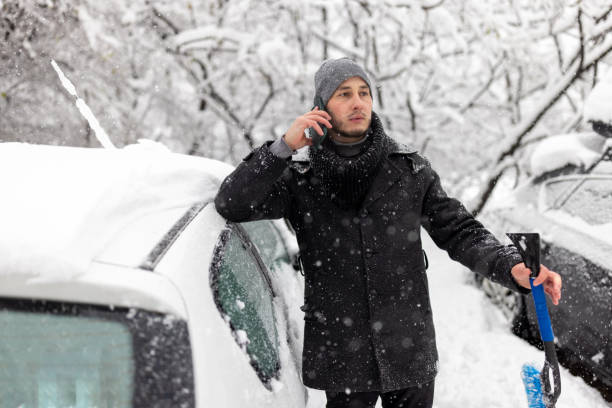 istock Young man in snow with broken down car. man calling the car service standing on the broken car in the winter 1359110350