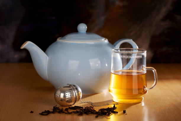 istock Glass with tea, tea infuser and blue teapot on wooden table. 1359112189