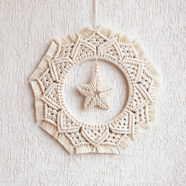 istock Christmas decor. Macrame wreath for Christmas and the new year on a white decorative plaster wall. Natural cotton thread, linen tape. Eco decor for home. Copy space 1359112295