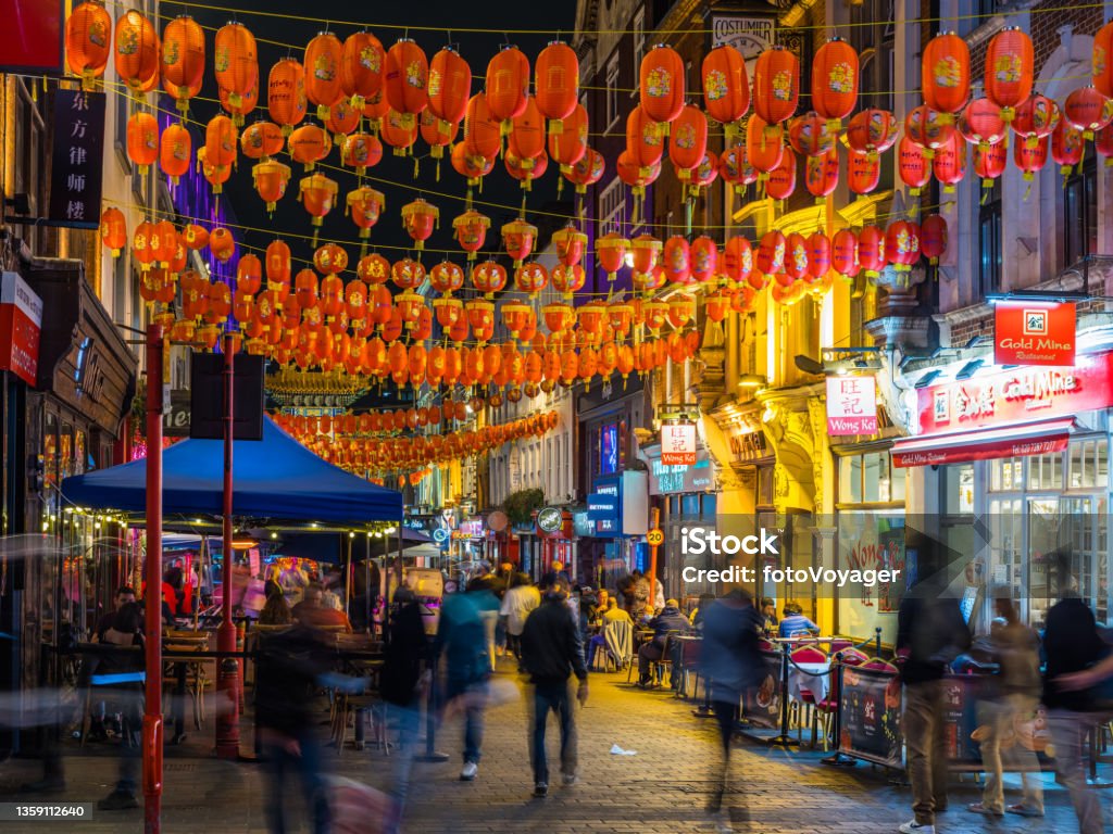 London Chinatown busy streets and restaurants beneath Chinese lanterns night Crowds of people enjoying the warm summer night in the busy pedestrianised streets of Chinatown, London. London - England Stock Photo