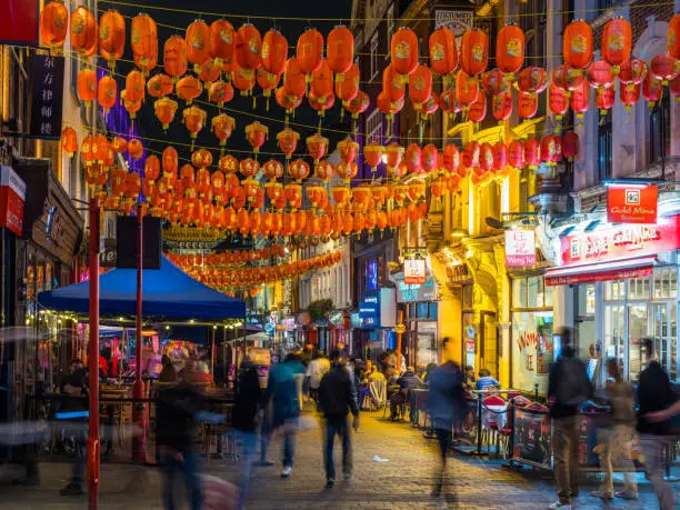 Crowds of people enjoying the warm summer night in the busy pedestrianised streets of Chinatown, London.