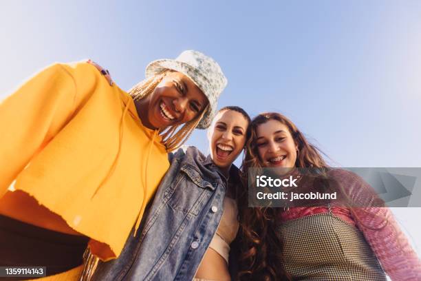 Low Angle View Of Three Friends Smiling Cheerfully Stock Photo - Download Image Now - Generation Z, Friendship, Smiling