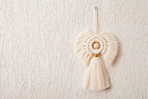 istock Christmas macrame decor. Christmas angel  on white wall. Natural materials - cotton thread, wood beads. Eco decorations, ornaments, hand made decor. Copy space 1359116136