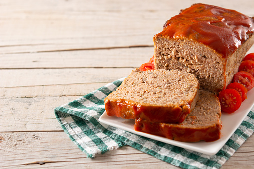 Traditional American meatloaf with ketchup on rustic wooden table