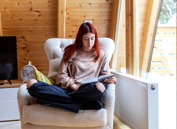 istock Young beautiful woman reading a book at home 1359118507
