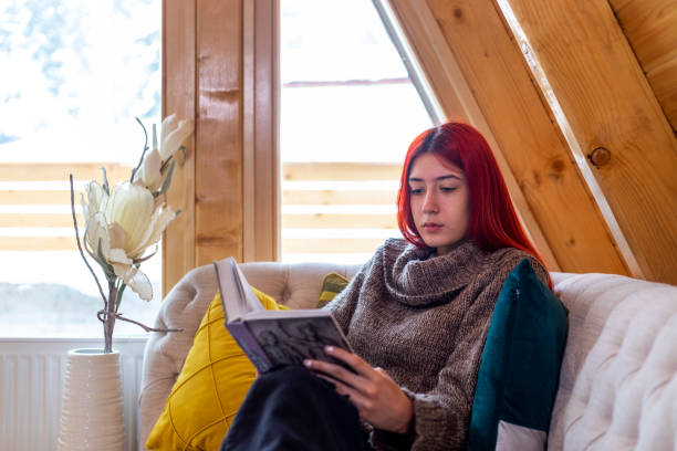 istock Young beautiful woman reading a book at home 1359118878