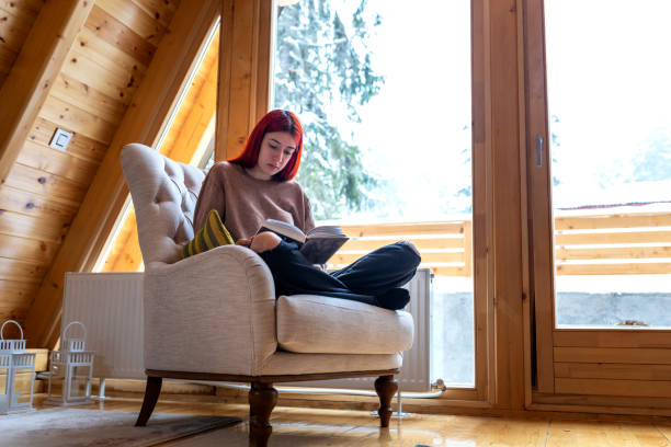 istock Young beautiful woman reading a book at home 1359118884