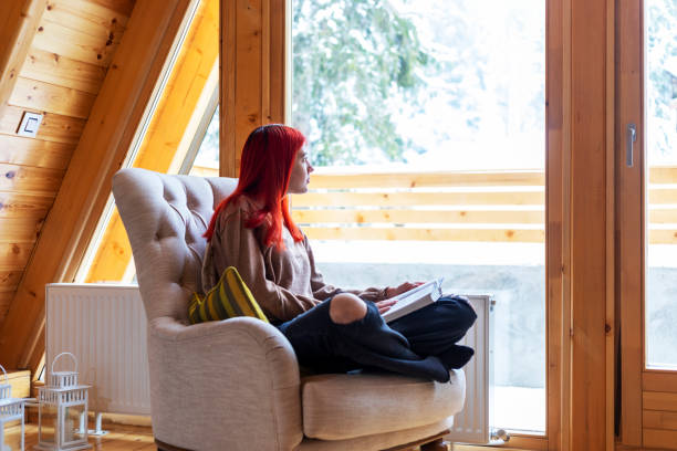 istock Young beautiful woman reading a book at home 1359118902