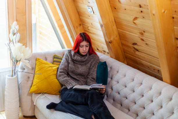 istock Young beautiful woman reading a book at home 1359118909