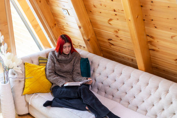 istock Young beautiful woman reading a book at home 1359118931