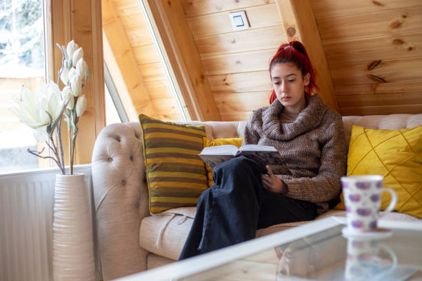 istock Young beautiful woman reading a book at home 1359118968