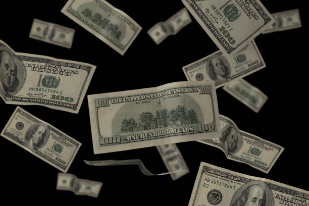 istock Flying 100 American dollars banknotes isolated on black background with copy space. 1359122771