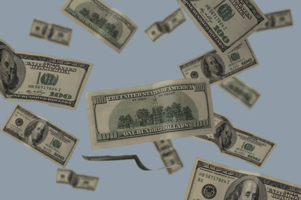 istock Flying 100 American dollars banknotes isolated on blue background with copy space. 1359122774