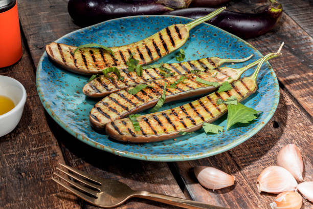 istock Grilled eggplants in blue plate on wood background. 1359125668