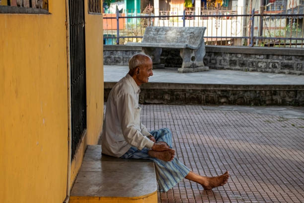 stock photo of 60 to 70 year old indian grandpa or senior citizen wearing casual cloths, sitting outside of the temple and enjoying evening at kolhapur, maharashtra, india. selective focus. - 60 70 year old imagens e fotografias de stock