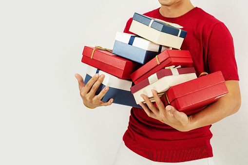Man in a red t-shirt carrying a stack of gift boxes - close-up shot. Clean white background with copy space.