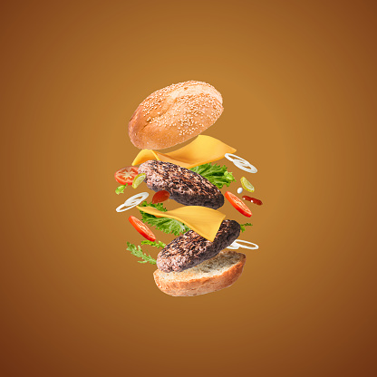 tasty cheese burger with flying ingredients on brown background with copyspace