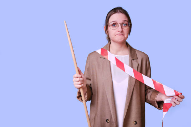 istock Sad female teacher holds a red and white tape on a studio blue background, copy space 1359128691