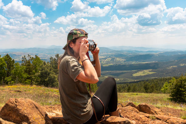 chica turista fotografiando con una cámara de fotos vintage en la cima del pico de la montaña - tourist photographing armed forces military fotografías e imágenes de stock