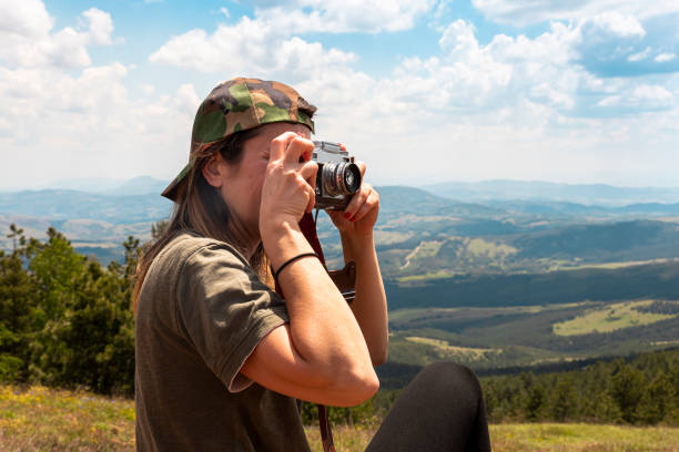 chica turista fotografiando con una cámara de fotos vintage en la cima del pico de la montaña - tourist photographing armed forces military fotografías e imágenes de stock