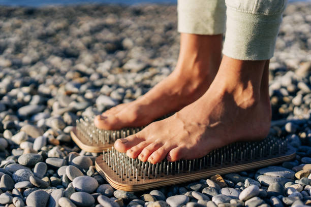 close up of female feet on boards with nails. - sadhu imagens e fotografias de stock