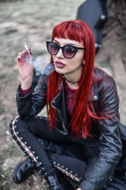 istock Beautiful Goth Redhead Female Smoking Cigarettes In Park 1359140429