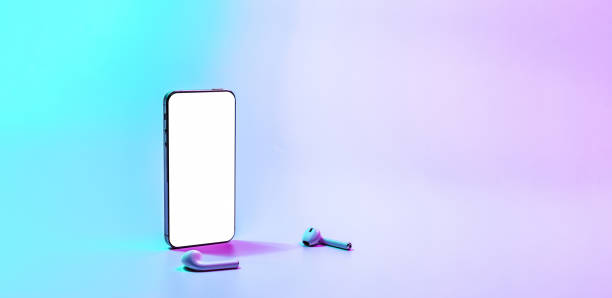 istock Mockup display. Mobile smart phone technology blank screen. Mock up smart phone device, audio headphones equipment on neon gradient banner background. Mockup for application, website design project. 1359141416