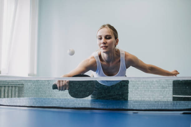 mittagspause freizeit, aktivitäten zum stressabbau, ansprechende büroaktivitäten. lustige bürospiele. ping pong turnier. junge geschäftsfrau spielt tischtennis, tischtennis im büro - table tennis tennis table indoors stock-fotos und bilder