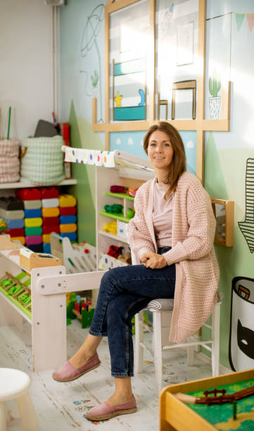 Nursery teacher sitting in the preschool play room stock photo