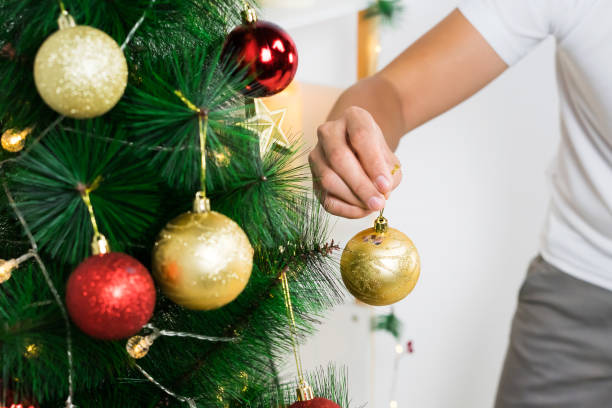 Man's hand decorating a Christmas tree. stock photo