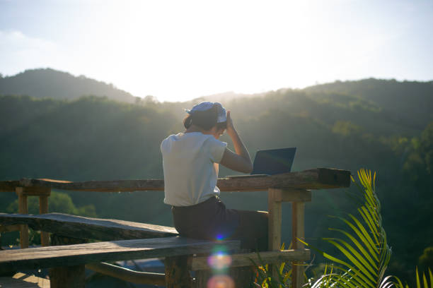 istock Woman using computer on a wooden table at sunset 1359144736