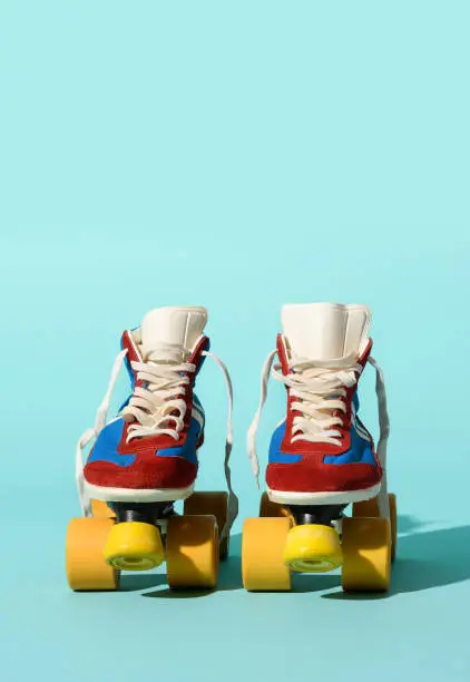 Isolated pair of old fashioned roller skates placed on light blue background in studio