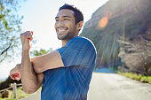 istock Shot of a handsome young man standing alone and stretching during his outdoor workout 1359149467