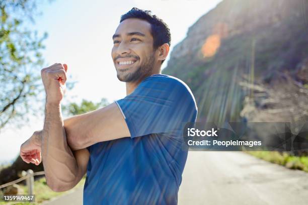 Shot Of A Handsome Young Man Standing Alone And Stretching During His Outdoor Workout Stock Photo - Download Image Now