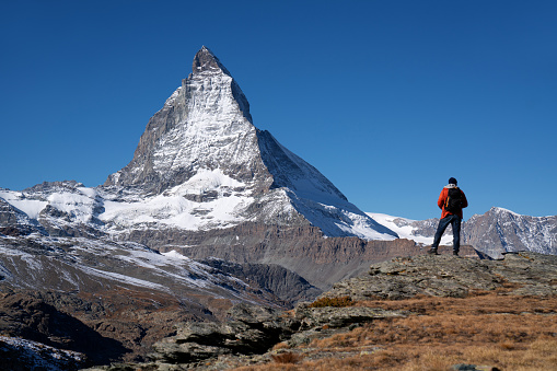 Young Caucasian man walking in nature near Matterhorn mountain in Switzerland\nalpine hiking