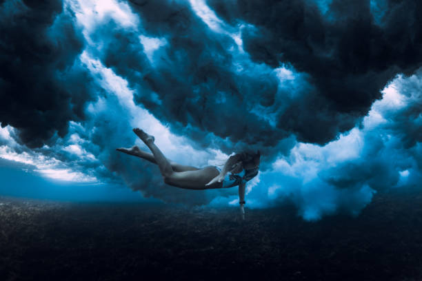 istock Woman swim under ocean wave. Duck dive under crashing waves 1359153029